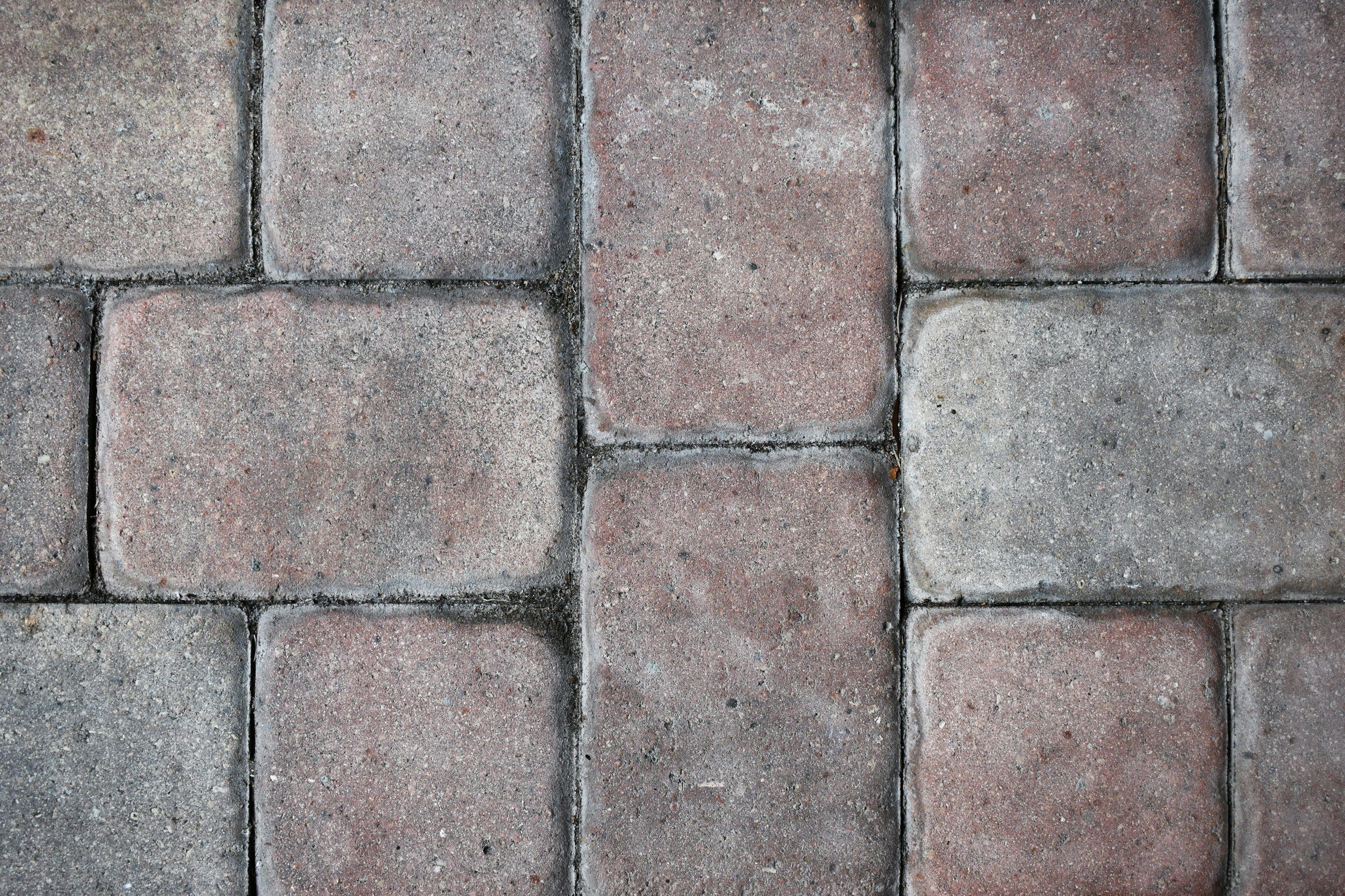 Close-up of tumbled concrete pavers in warm red and grey tones