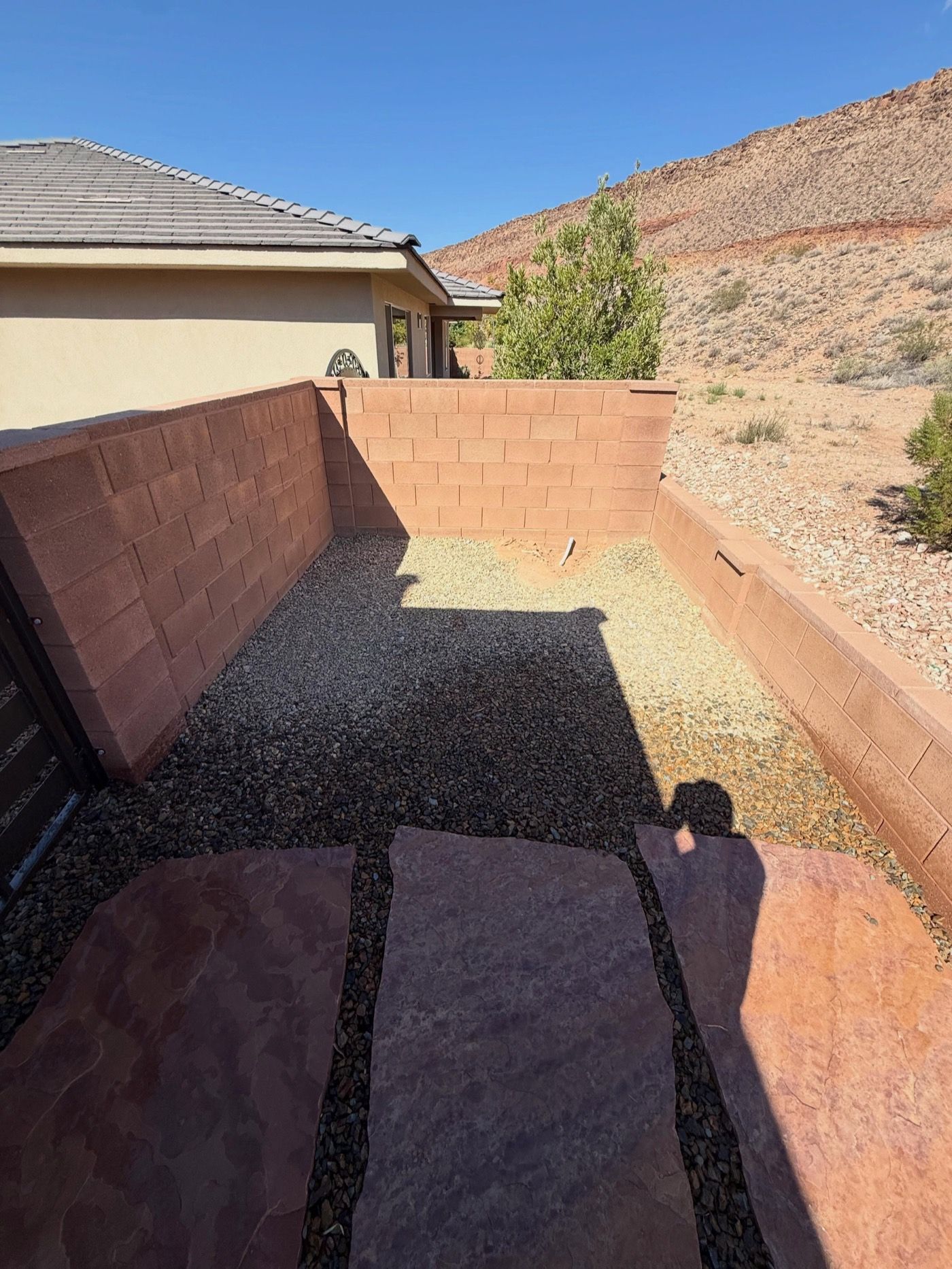 Walled side yard with red flagstone stepping pads set in dark rock